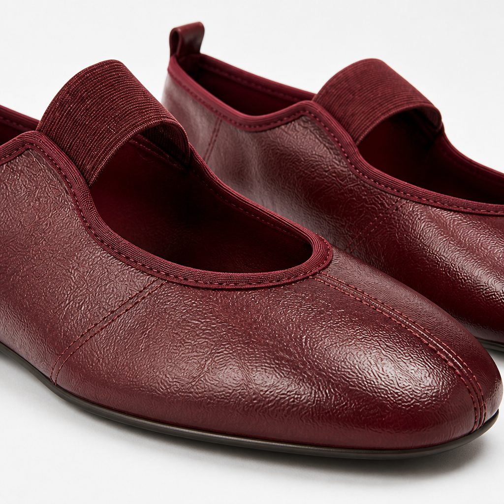 Close-up detail of burgundy flats showing texture stitching strap and rounded toe