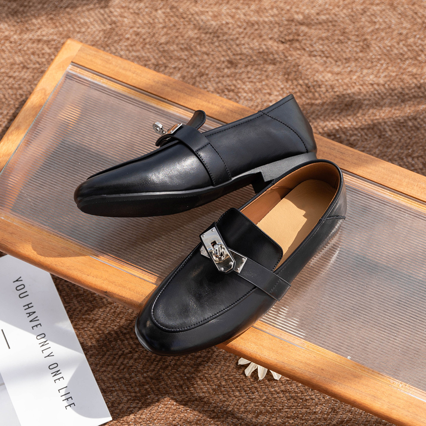 Mocassins noirs disposés sur une surface texturée, vus de dessus en biais.