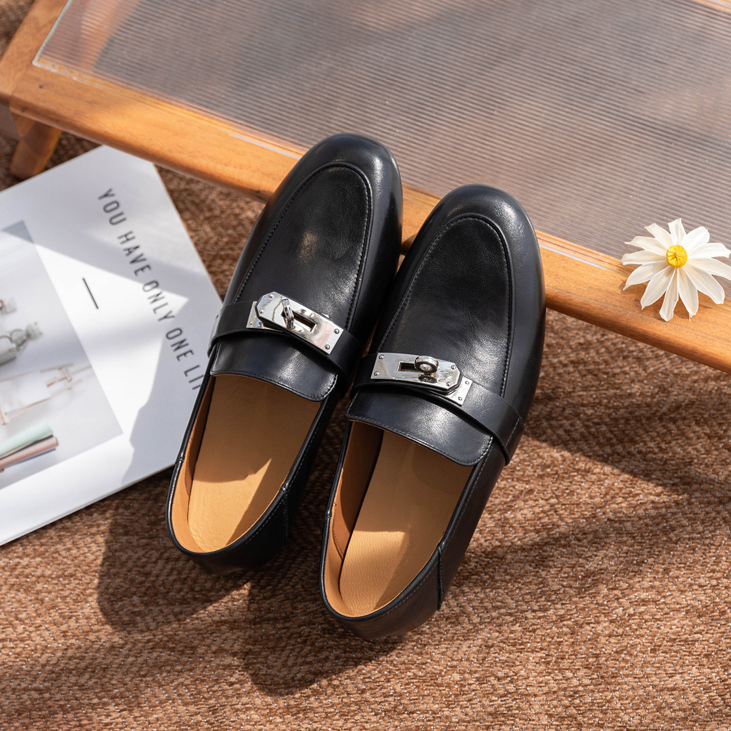 Une paire de mocassins noirs dans un contexte lifestyle avec accessoires.
