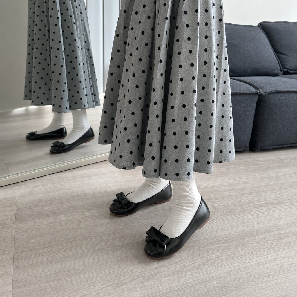 Zwarte glanzende ballerina's met strik, gedragen met een rok en sokken.