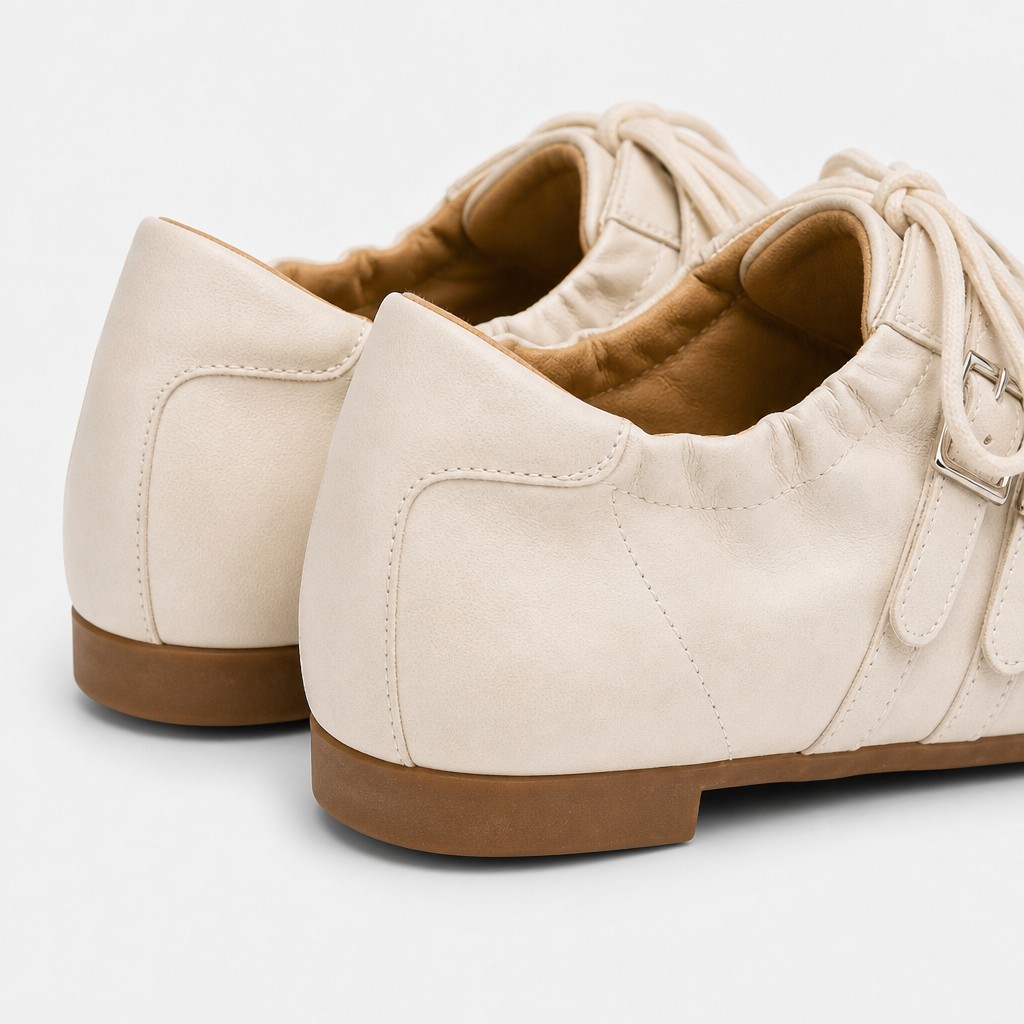 Close-up van de achterkant en zijkant met stiksels op de hiel en afwerking op crèmekleurige platte schoenen
