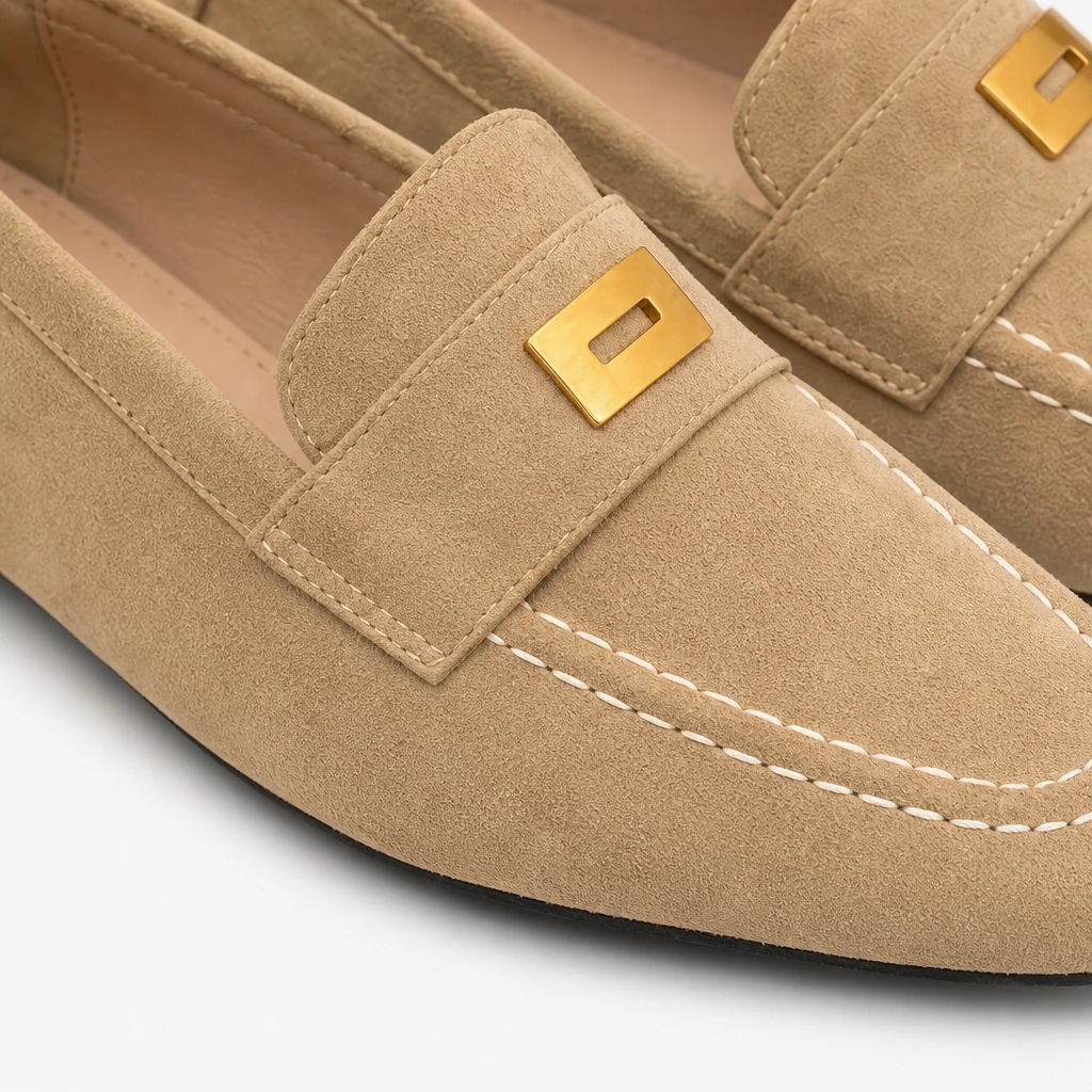 Lähikuva mokkanahkaa näyttävästä penny loafer -tekstuurista, ompeleista ja metallista